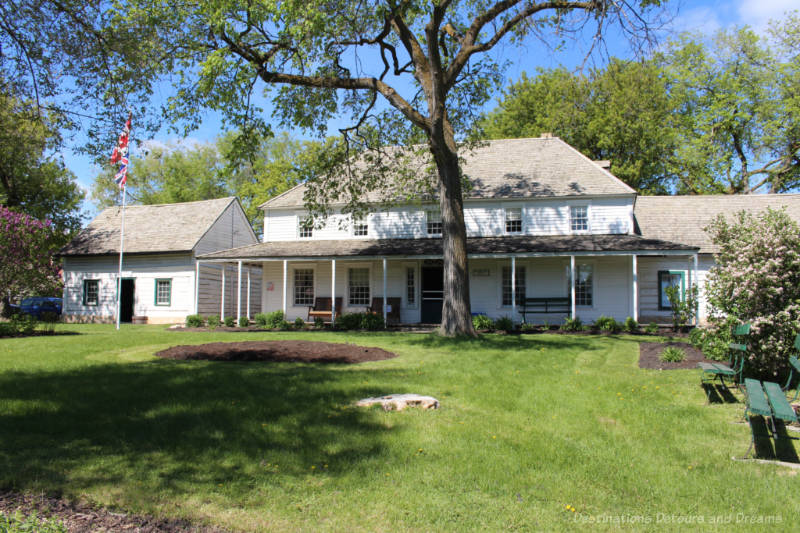 Two story white wood frame 19th century house museum with covered area running the front of the house