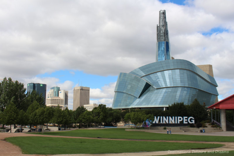 Winnipeg sign in front of the Canadian Museum for Human Rights Building and the Winnipeg skyline