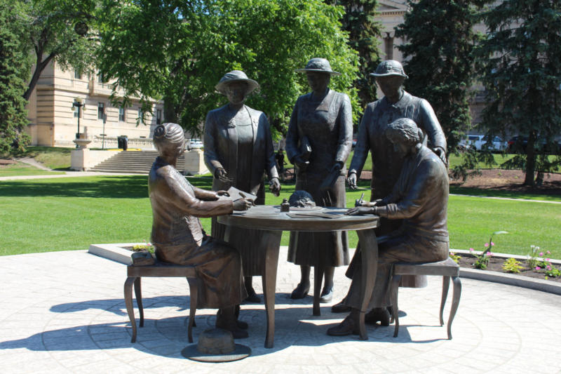 Statue of five women, two seated at a table and three standing representing the five women instrument in the Persons Case in Canada