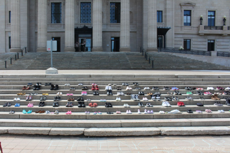 Pairs of shoes lined up on the stone steps of the Manitoba Legislative Building in memory of the children in unmarked graves on residential school sites