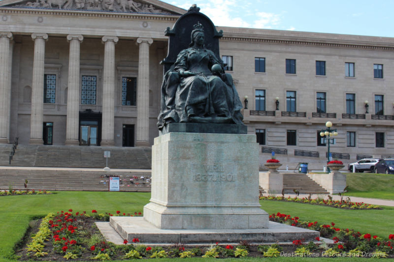 Statue of Queen Victoria sitting on the grounds in front of the Manitoba Legislative Building