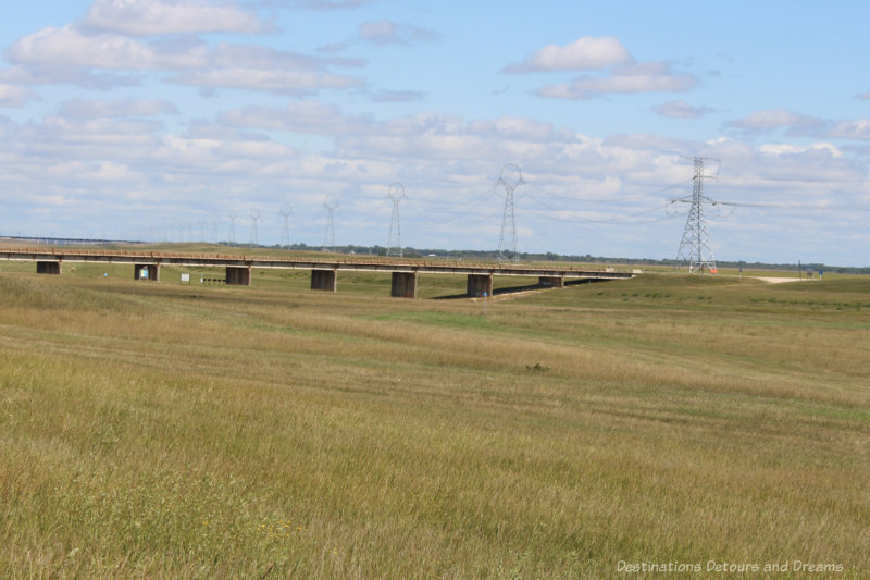 A grassy large ditch, free of water, running under a bridge