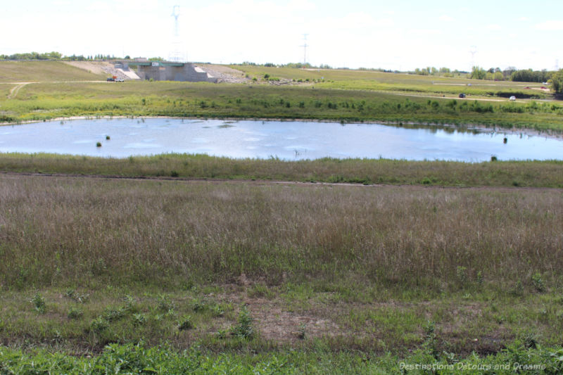 A pond of water surrounded by prairie -  a channel left from Red River Floodway construction