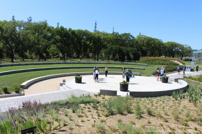 A cement stage in the centre of the Gardens at the Leaf in Winnipeg, Manitoba with gentle tiered seating on the lawn in front of it