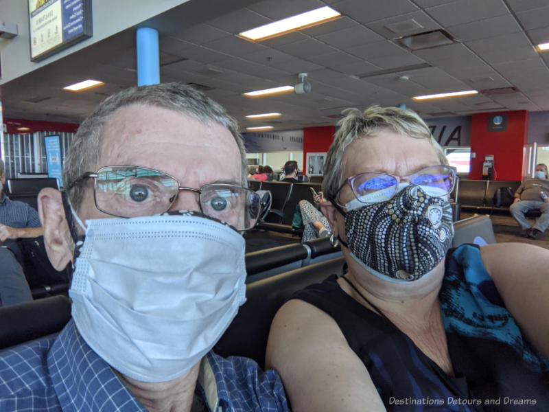 Man and woman wearing face masks inside airport terminal