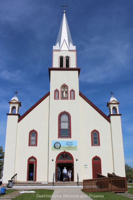 White former church with reddish trim, centre steeple, and side spires