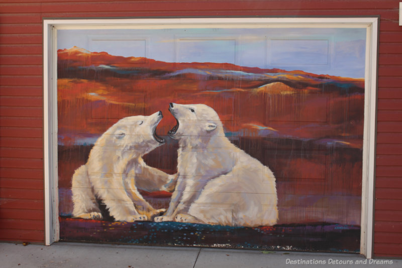 Mural of two polar bears against an reddish tundra background painted on a garage door in Back Alley Arctic Alley in Winnipeg