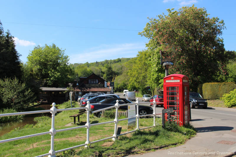 English country pub alongside a small river in Gomshall near an intersection with a red telephone box in the foreground 