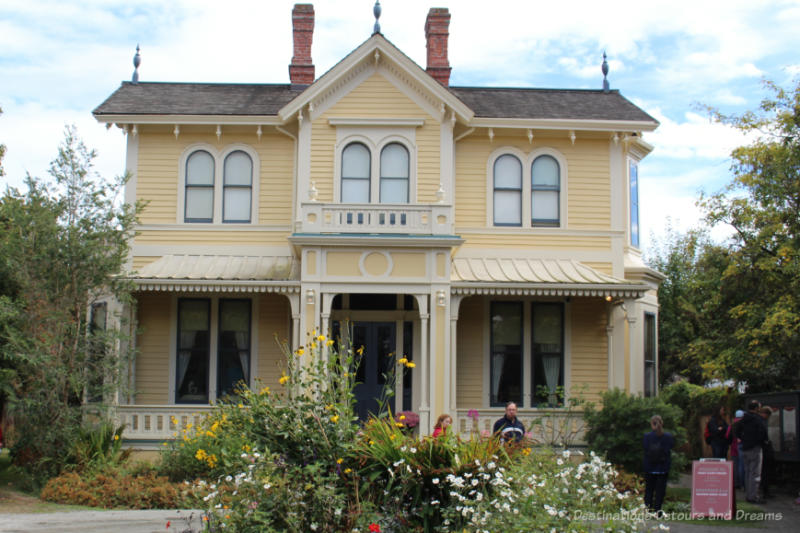 Yellow two-story wood house with white trim and veranda