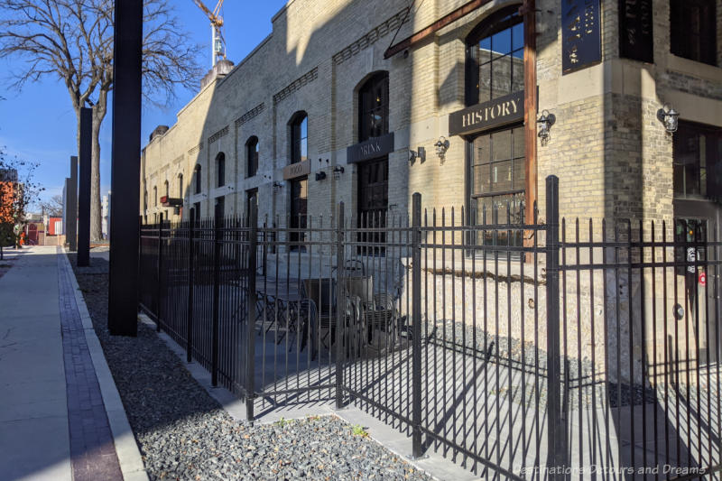 Iron-fenced restaurant patio area at the side of an historic brick building