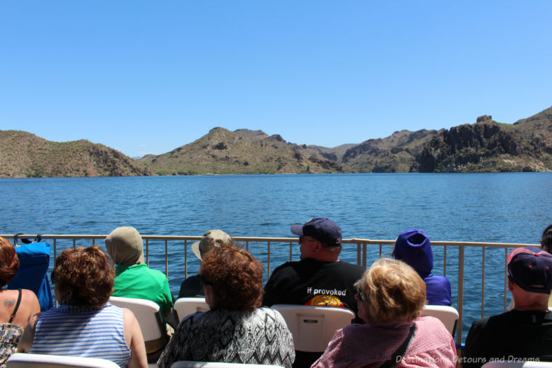 People seated on the open deck of a boat cruising Saguaro Lake in Arizona