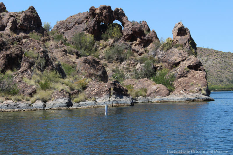 An unusual rock formation with desert shrubs on Saguaro Lake