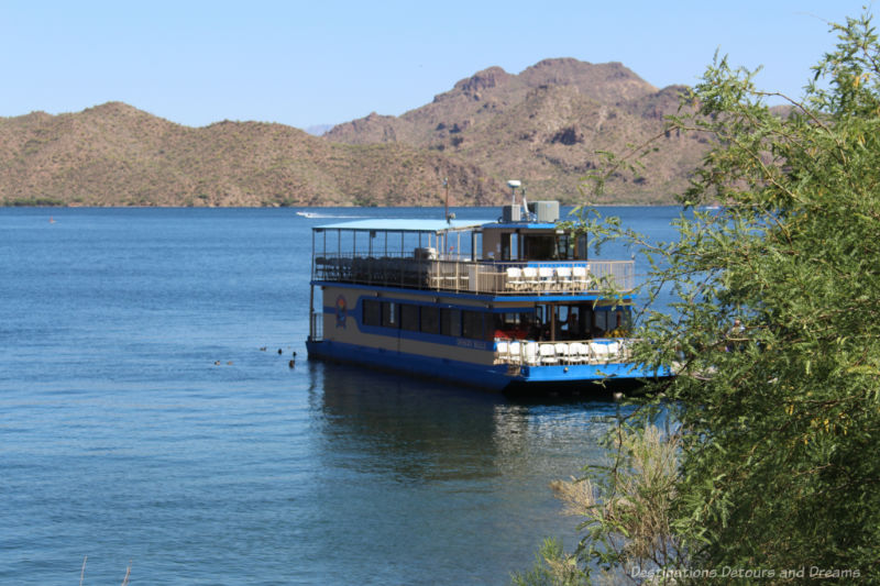 Two-level cruise boat on a lake surrounded by desert mountains in Arizona