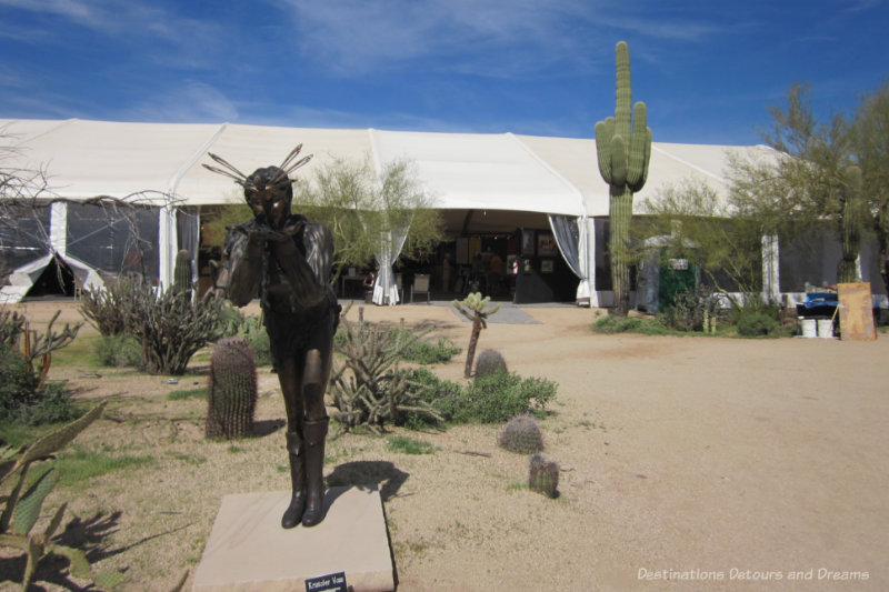 Statues in a desert courtyard surrounded by show tents at Arizona Fine Art Expo