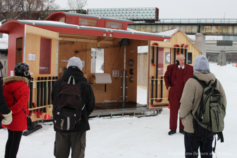 Al Simmons talking to crowd in front of his opened-up caboose-like warming hut