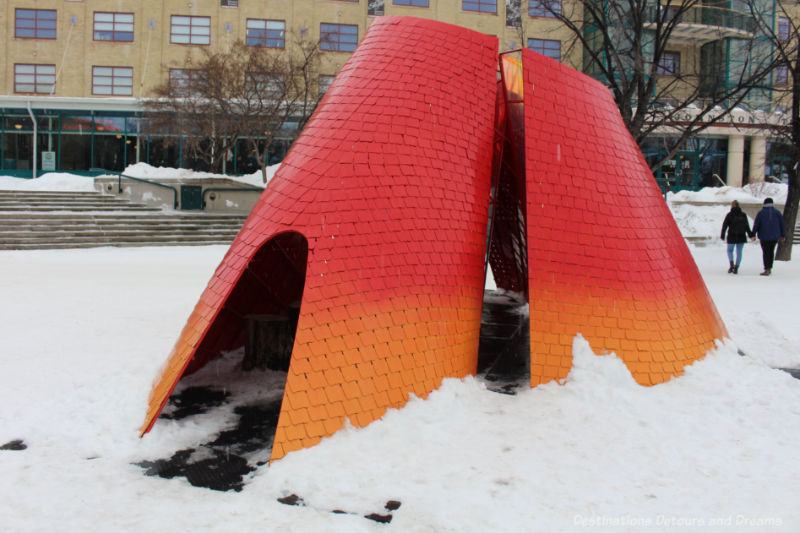 Warming hut designed after a butterfly wings in radiant colours of orange and red