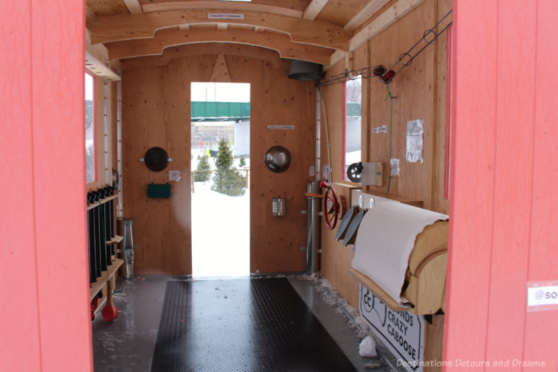 The wooden interior of a caboose-like warming hut with a variety of noise and music-making gadgets affixed to the walls.