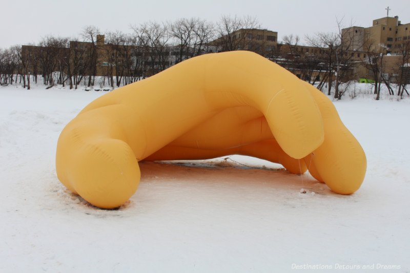 A large inflated yellow hand structure cupped to create a warming shelter
