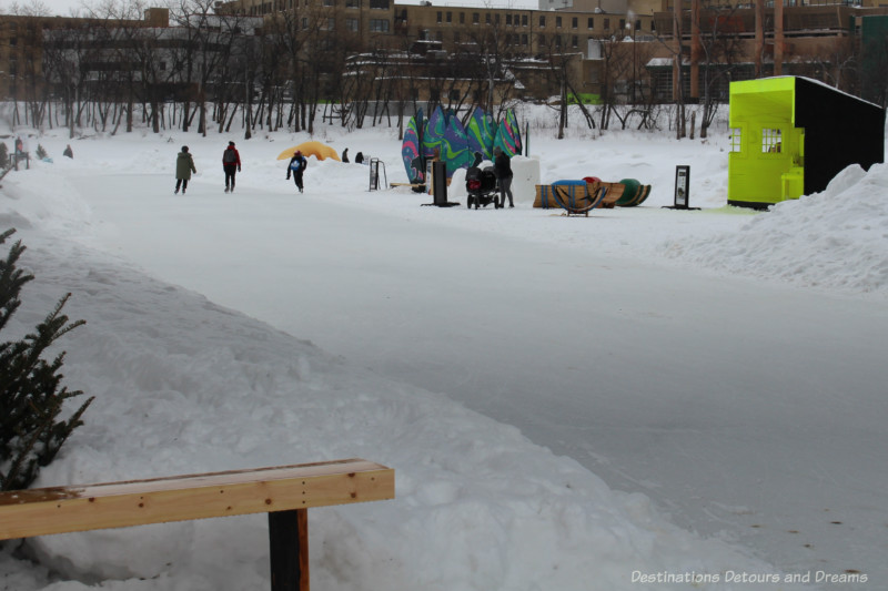 Skating trail on the river with artful warming huts on one side of the trail.