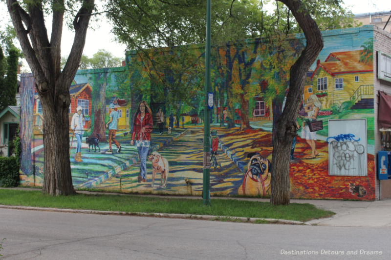 Mural on the side of a building in Winnipeg's Wolseley neighbourhood showing people walking, cycling, or walking their dogs in a tree-lined neighbourhood