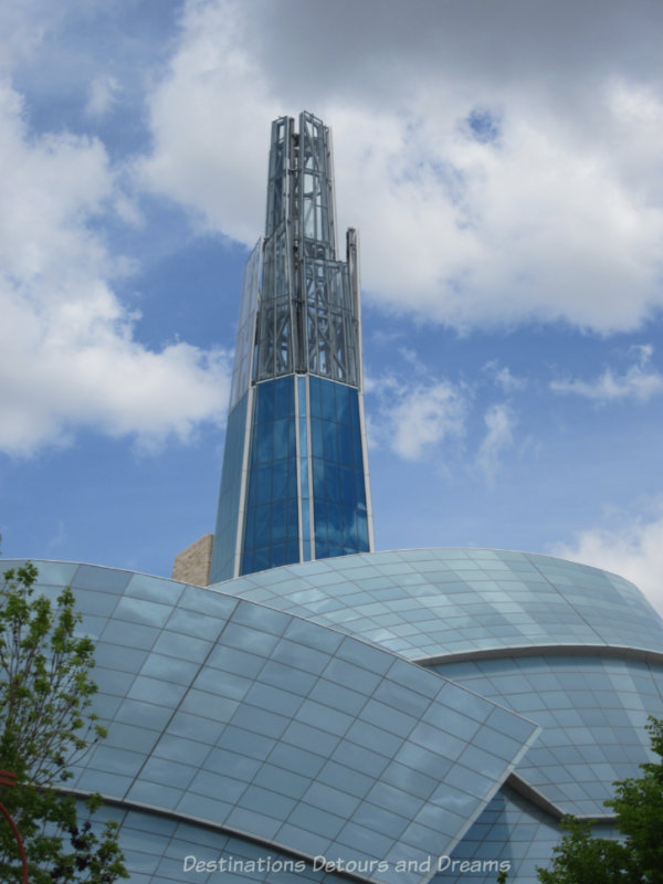Steel and blue glass Tower of Hope rising from the glass wings of the Canadian Museum for Human Rights building