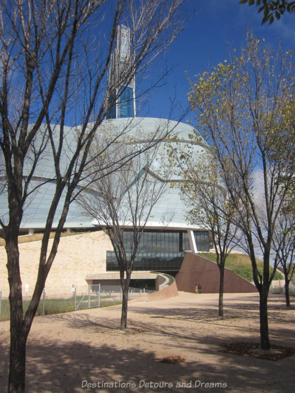 Paved pathway sloping gently downward and leading into the entrance of the CMHR