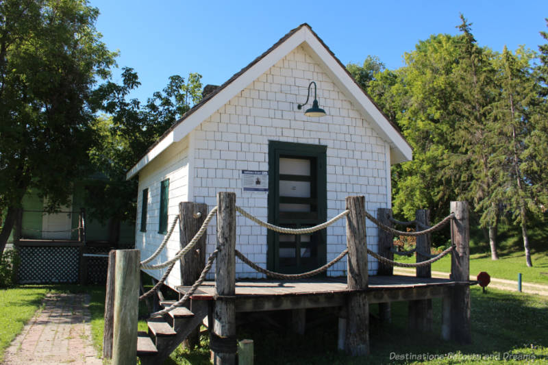 Small white wooden cottage with green door that once was a lighthouse keeper's house