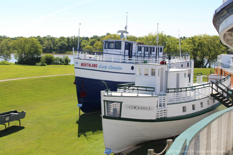 Two historic shipping vessels on a lawn at a marine museum