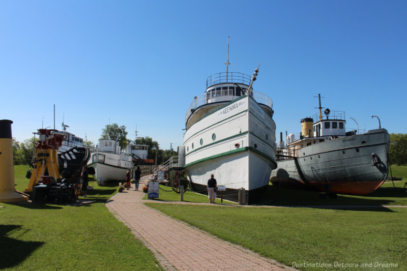 Several ships resting on a lawn at the Marine Museum of Manitoba