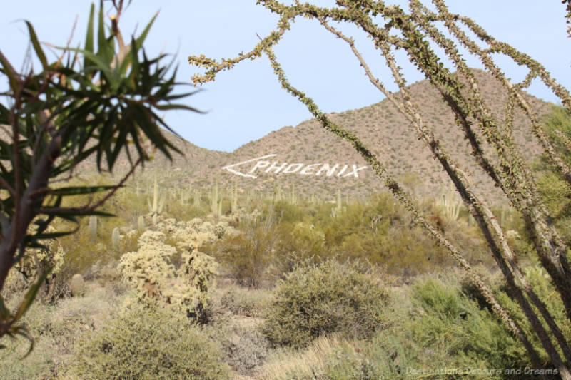 Phoenix sign painted in white on a desert mountain with an arrow pointing left