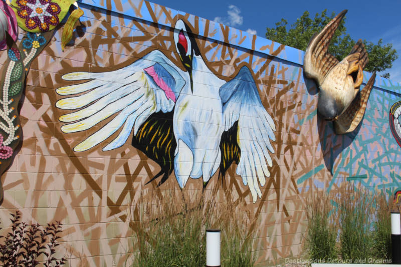 Part of a endangered species-themed mural along an outside wall feature a painting of a whooping crane and a 3-D representation of a Peregrine falcon