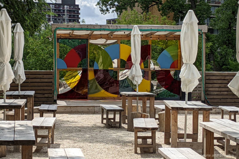 Open booth stage at the edge of a large patio area filled with wooden tables and benches