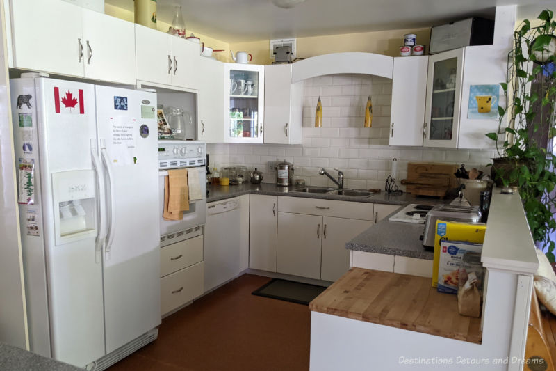 U-shaped kitchen with white cabinetry, appliances, and backsplash and grey countertop at Moon Gate Guest House