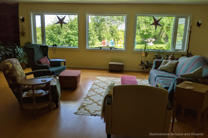 Sofa and chairs in a large sitting area with big windows looking out on a grassy area