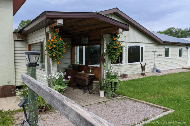 Front of a single story guest house with cream-coloured siding and a covered entryway in front of door