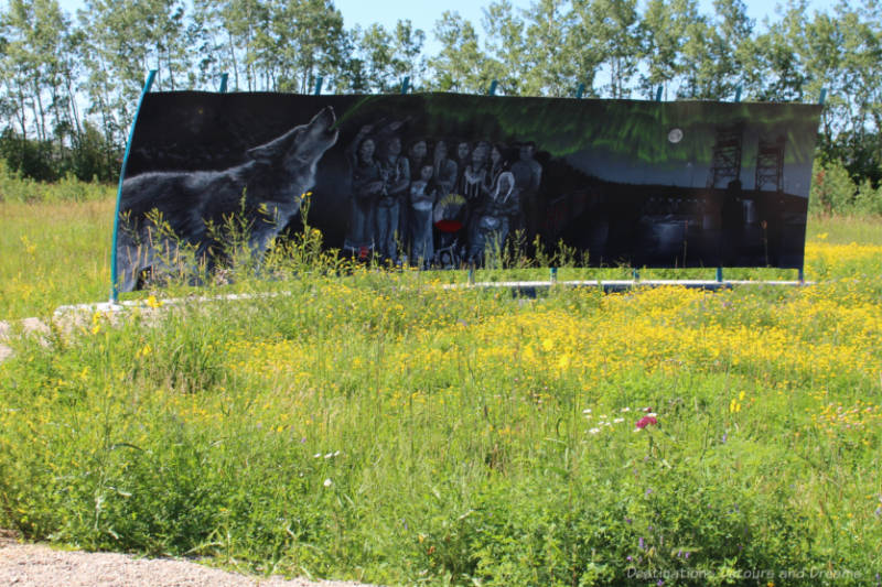 Murals in shades of grey show night scene with howling wolf, a group of people, and electrical transmission towers