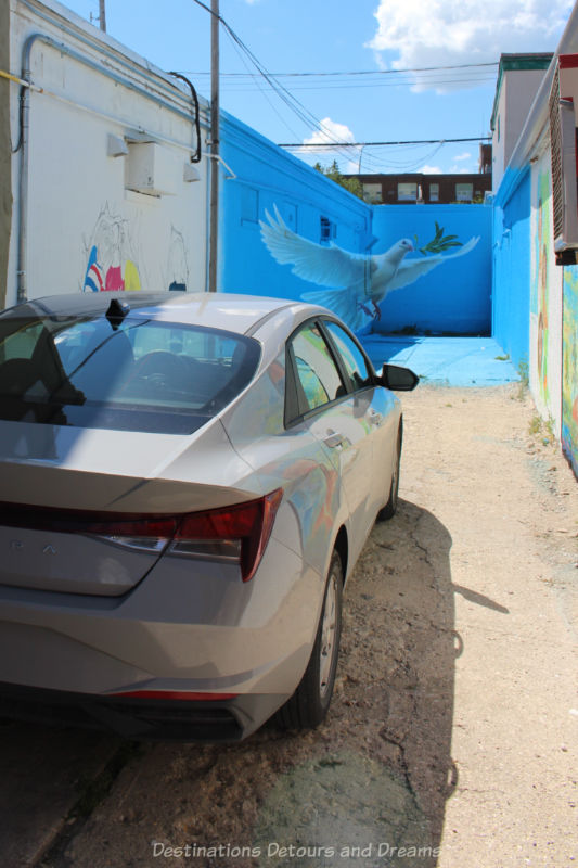 Car parked in a dead end alley with paintings on the walls of the alley