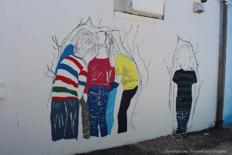 Mural showing the backs of several children huddled together and another one with head hung low off to the side