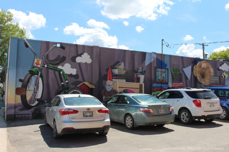 Mural showing a collage of nostalgic items with cars parked in front of it