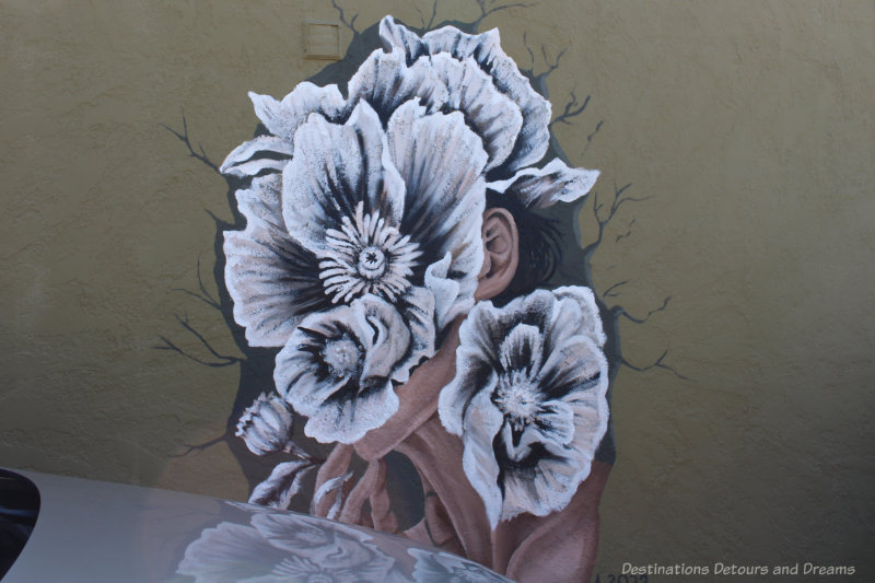 Murals showing a collection of white flowers with black lines covering a female face