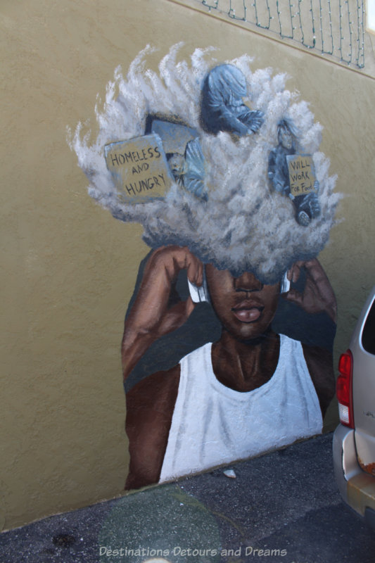 Murals showing a male in a white t-shirt with the top part of his head covered in a cloud with homeless people in it