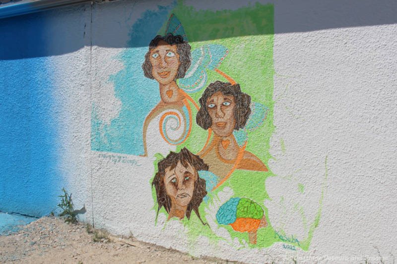 Murals on a stucco wall with the faces of three women