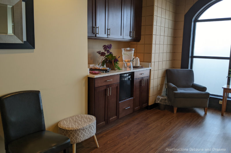 Chairs beside dark wood cabinet area containing refreshments at a spa