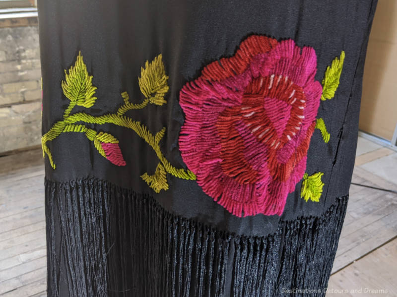 Close-up of a large rose-coloured flower embroidered on a dress