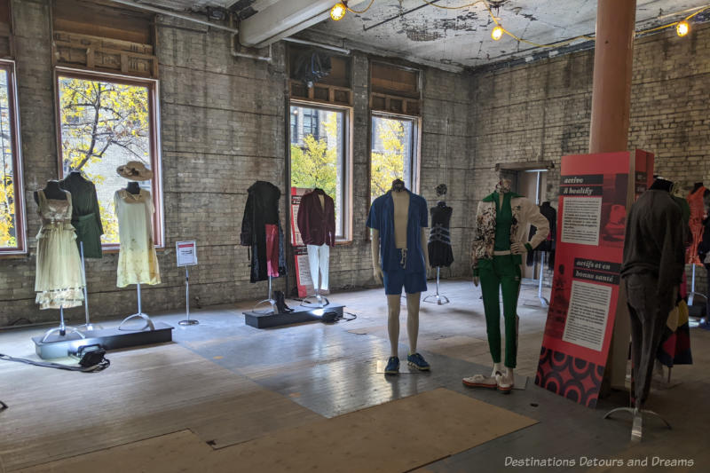 Headless mannequins standing in a large brick walled room and displaying a variety of clothing as part of the Viral Fashion exhibit.
