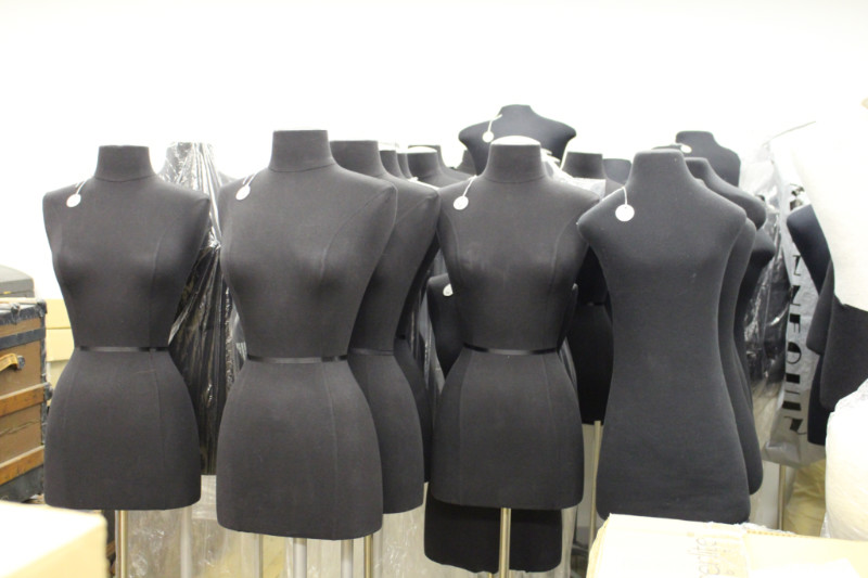 A collection of headless mannequins with grey torsos used to display costumes