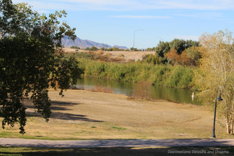 Small river with shrubs on either side and view of mountains in background