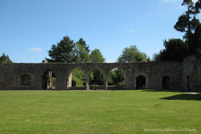 Green grassed are with the stone ruins of a Cistercian abbey in the background