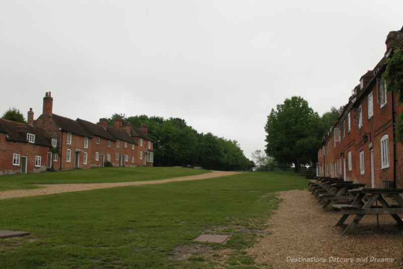 Rows of eighteenth century brick cottages on either side of grass area and path leading to river