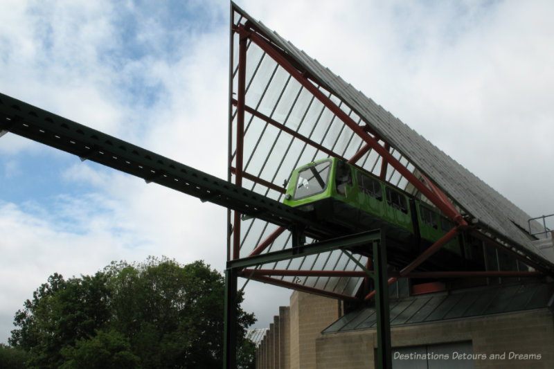 Green monorail train entering the pointed roof area of a museum